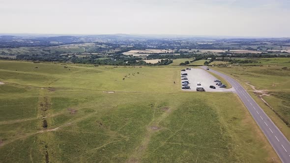 AERIAL VIEW from drone approaching moorland car park with livestock off to the left and road to the