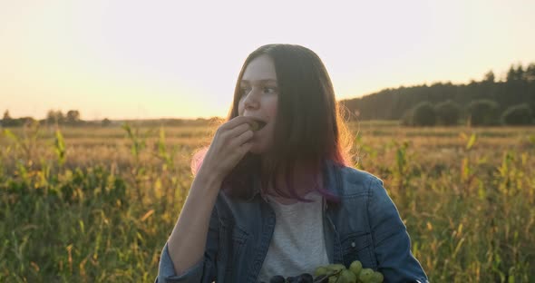 Young Girl Holding Basket of Grapes and Eating Grapes