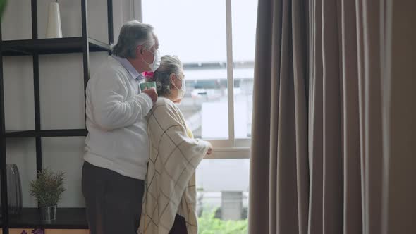 asian retired elderly couple wearing face masks watch the world