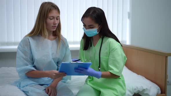 Positive Caucasian Teenage Patient and Female Doctor Talking Discussing Case History Sitting on Bed