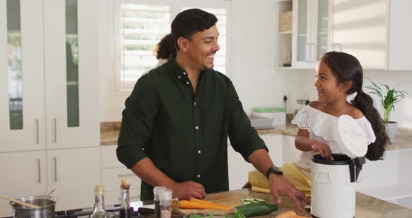 Hispanic parents and daughter cooking and teaching segregating bio trash