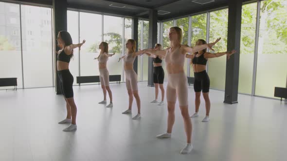 Group of Flexible Ladies Training with Coach at Dance Studio Practicing Tilt Aside Pas in Light Room