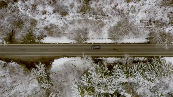 Watching a driving car from above having a ride through a winter landscape in a woodland