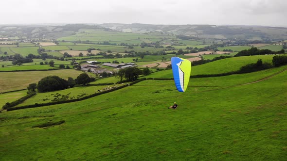 Aerial shot of a Paraglider flying over a field and Countryside in East Devon England