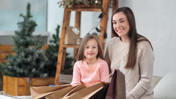 Laughing Young Beautiful Woman Pose with Female Little Child Having Xmas Paper Shopping Bag