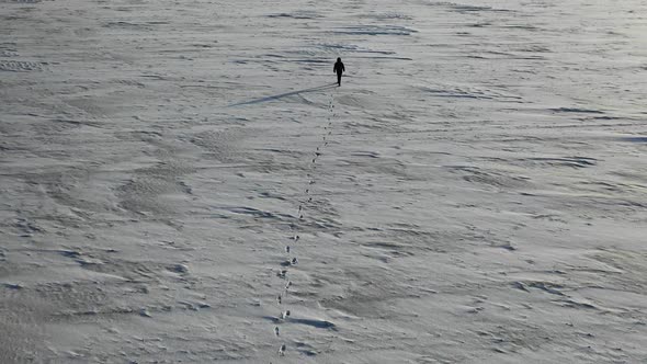 Aerial View of a Human with Heavy Backpack Walking By Snow Desert in Alaska