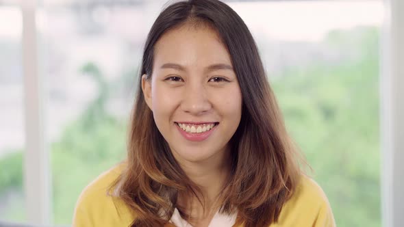 Asian woman feeling happy smiling and looking to camera while relax in her living room.