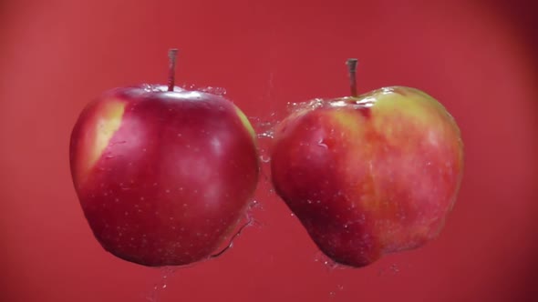Two Juicy Red Apples Colliding on a Red Background in Slow Motion