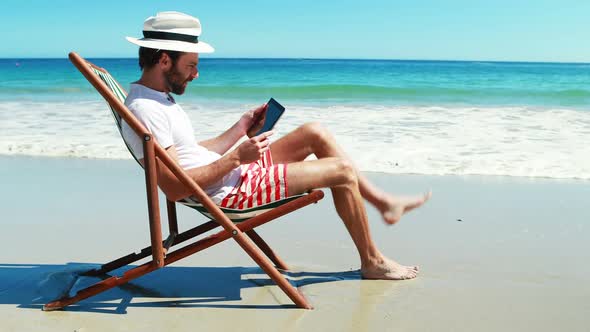 Man using digital tablet at beach