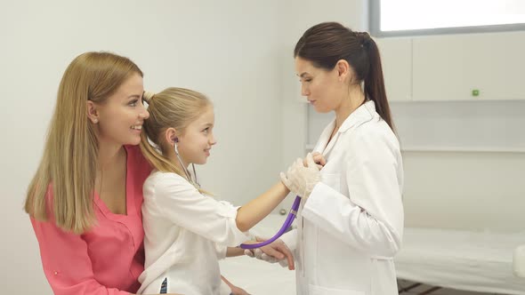 Joyful Diligent Child Girl Playing with Stethoscope in Hospital