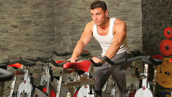 Handsome Man Riding a Bike in Gym
