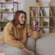 Pretty Happy Smiling Caucasian Young Woman Talking on Video on Phone While Sitting on Sofa in Room - VideoHive Item for Sale