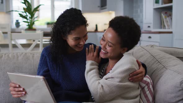 Mixed race lesbian couple sitting on couch and