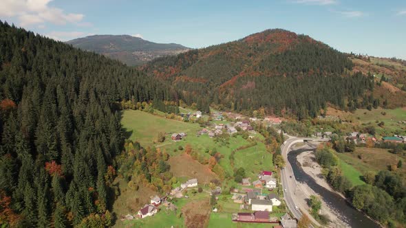 Aerial View of a Mountain Village Along the River in the Middle of a Sunny Summer Day