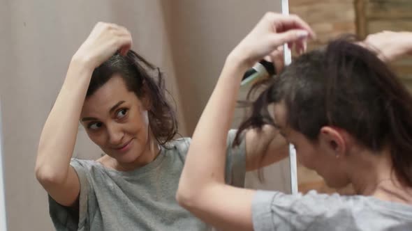 Cute Woman Hairdresser in a Gray Tshirt Shaves Hair with an Electric Machine for Haircut While