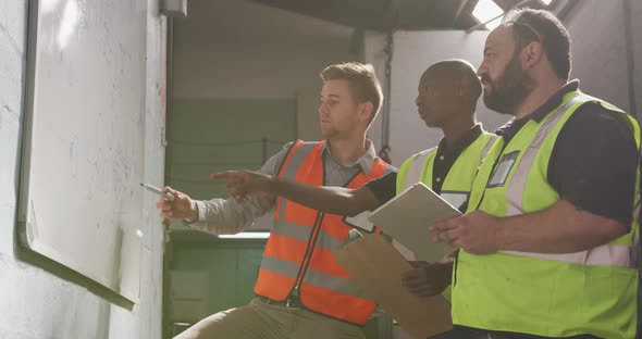 Two Caucasian and an African American male factory worker at a factory in discussion