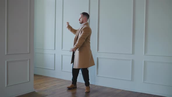 Young Man in Coat Dancing is Happy Successful Man