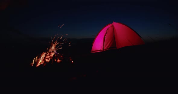 Camping Tent and Campfire at Night in Mountains