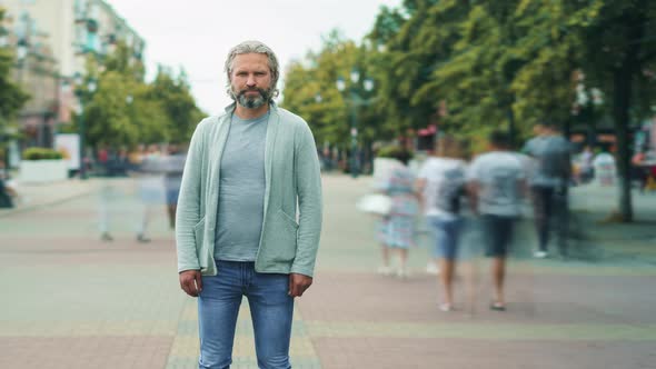 Zoomout Time Lapse of Grayhaired Man in Casual Clothing Standing Outdoors in Busy Street