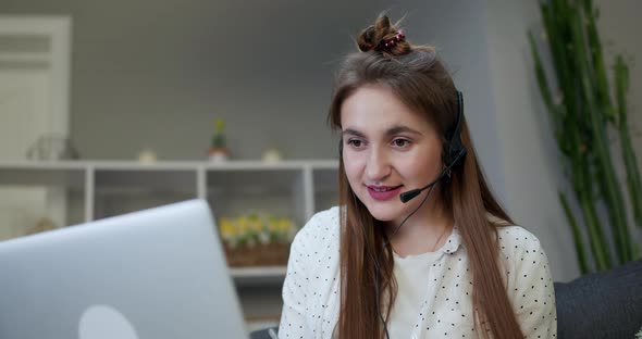 Girl Wearing Headphones Listening to Audio Course Using Laptop at Home