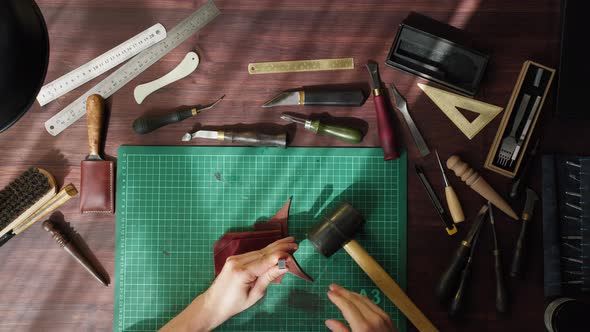 Craftman Knocking Making Holes in Brown Leather Using Professional Tools on Table at Leather