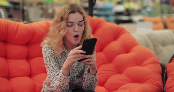 Coquette Woman Using Smartphone Sitting on Orange Sofa