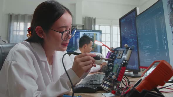 Development Facility: Beautiful Asian Female Engineer Does Computer Motherboard Soldering