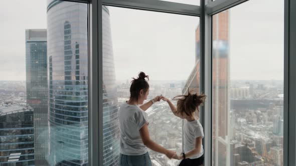 Active Young Mother and Cute Little Daughter Jumping Dancing in the Bedroom of a Modern House with a