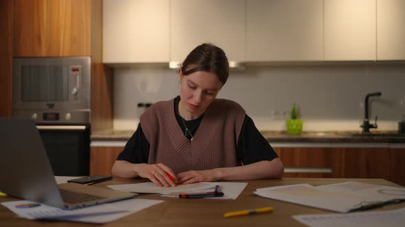 A Pensive Woman Looks at the Documents and the Graphs on the Table Make Notes in the Papers