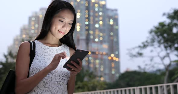 Woman using smart phone in city at night 