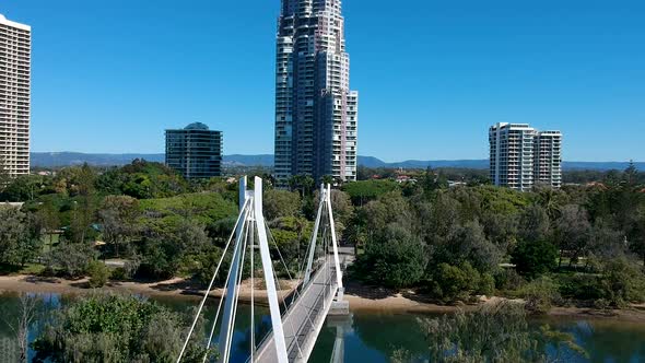 A pedestrian bridge leading into a park near a large city