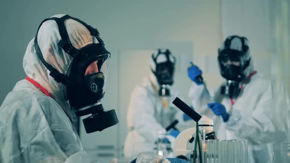 Lab Worker in a Hazmat Suit Is Using a Microscope During COVID-19, Coronavirus Antibodies Research