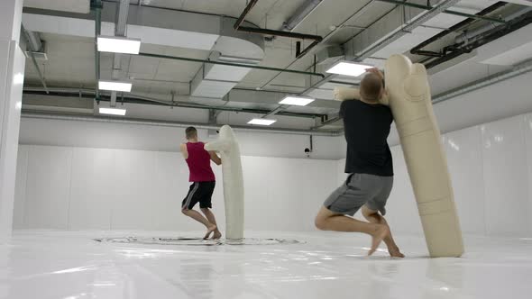 A Man in a Black Tshirt Fulfills Throws with a Scarecrow on the Tatami