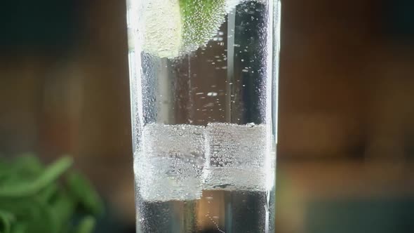Ice cubes covered with bubbles rise up in a clear glass of sparkling water