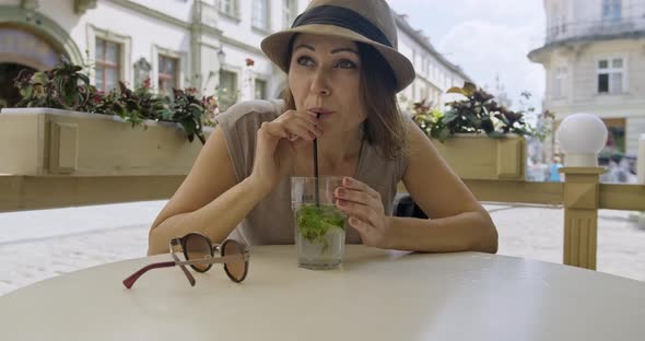 Mature Smiling Woman Relaxing and Drinking Drink with Mint Lime