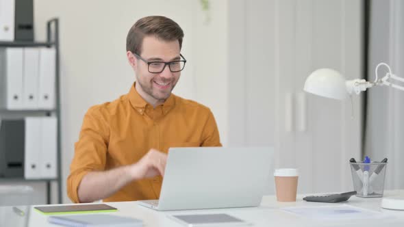 Video Chat on Laptop By Young Man in Office