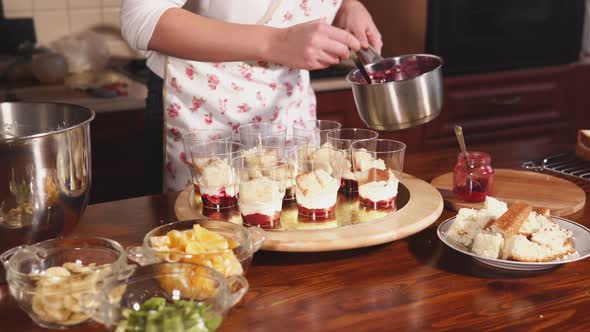 Woman Is Flooding a Fruit Dessert By Berries Liquid Marmalades in a Kitchen