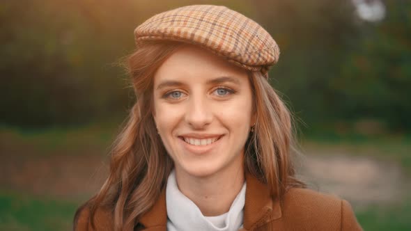 The Young Girl Is Smiling in a Forest and Is Looking at Camera