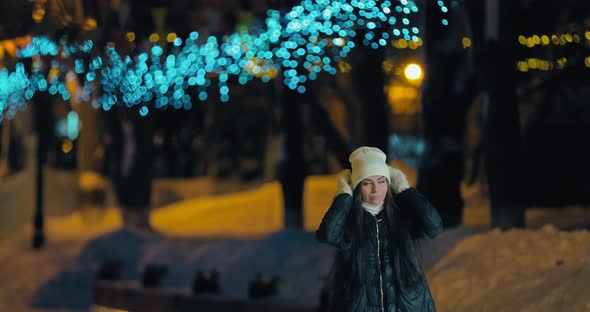 Beautiful Woman Walks Through the Winter City in the Evening