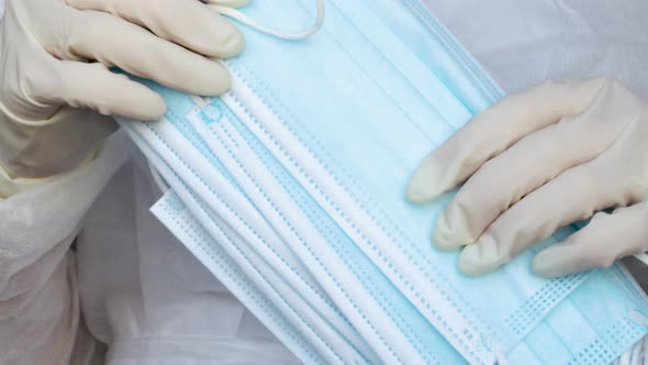 Woman doctor is holding a lot of medical protective face mask.white gloves on hands. Concept of coro