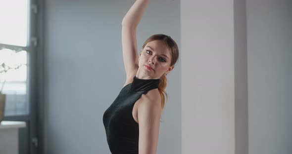 Attractive Young Woman Dancer in Black Dress with Open Back Rehearses Dance Moves, Ballet Rehearsal