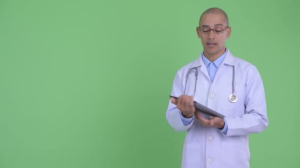 Happy Bald Multi Ethnic Man Doctor Talking and Showing Digital Tablet