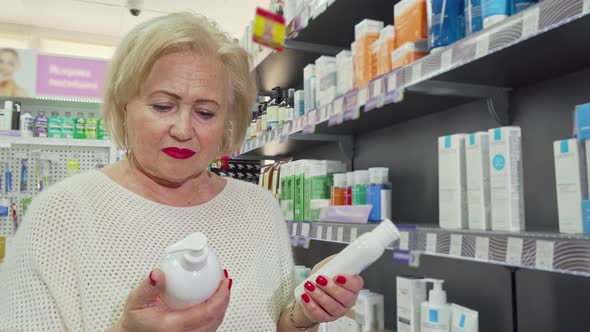 Lovely Senior Woman Smiling, Choosing Between Two Products at the Drugstore