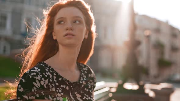 Beautiful Redhead Teen Girl Thoughtfully Adjusts Hair and Looking Away with Pen in Hand in