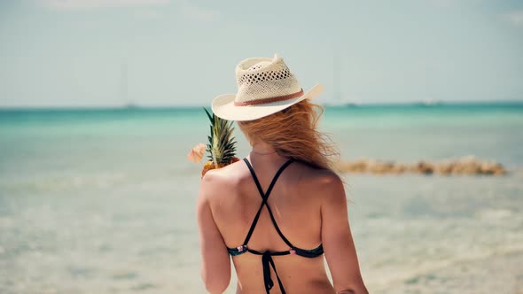Girl In Bikini Walking On Tropical Hawaii Beach. Woman In Swimsuit And Hat Walks Along Beach.