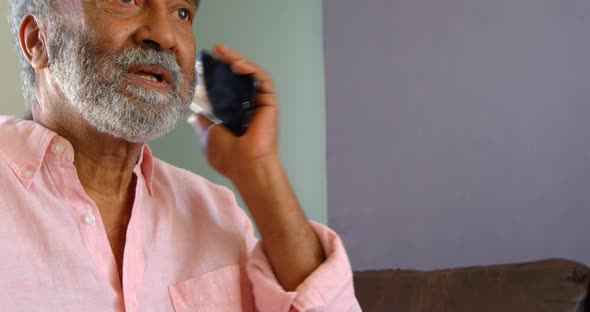 Side view of old asian senior man talking on mobile phone at home 4k