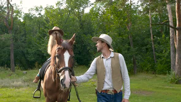 A Young Cowboy is Leading a Horse on Which His Daughter is Sitting