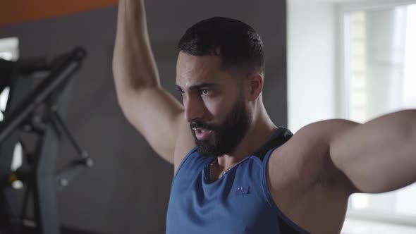 Close-up of Confident Perspiring Sportsman Training Shoulder and Back Muscles in Gym