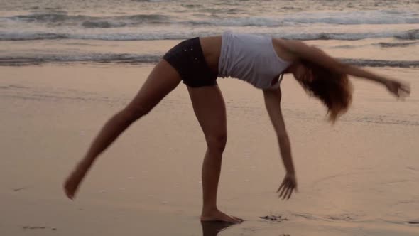 Young Woman Doing Cartwheels on Ocean Shore