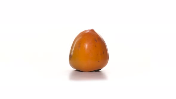 Appetizing Persimmon Lies on the Table and Rotates on a White Background